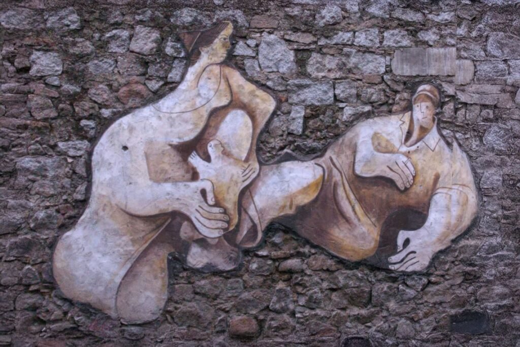 Mural representando um homem e uma mulher segurando uma pomba juntos, simbolizando paz e colaboração, em uma parede de pedra texturizada em Orgosolo, Sardenha.