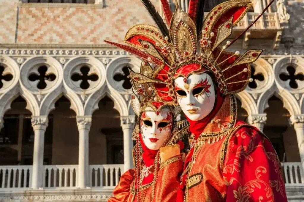 Casal com trajes e máscaras tradicionais diante do Palazzo Ducale no Carnaval de Veneza